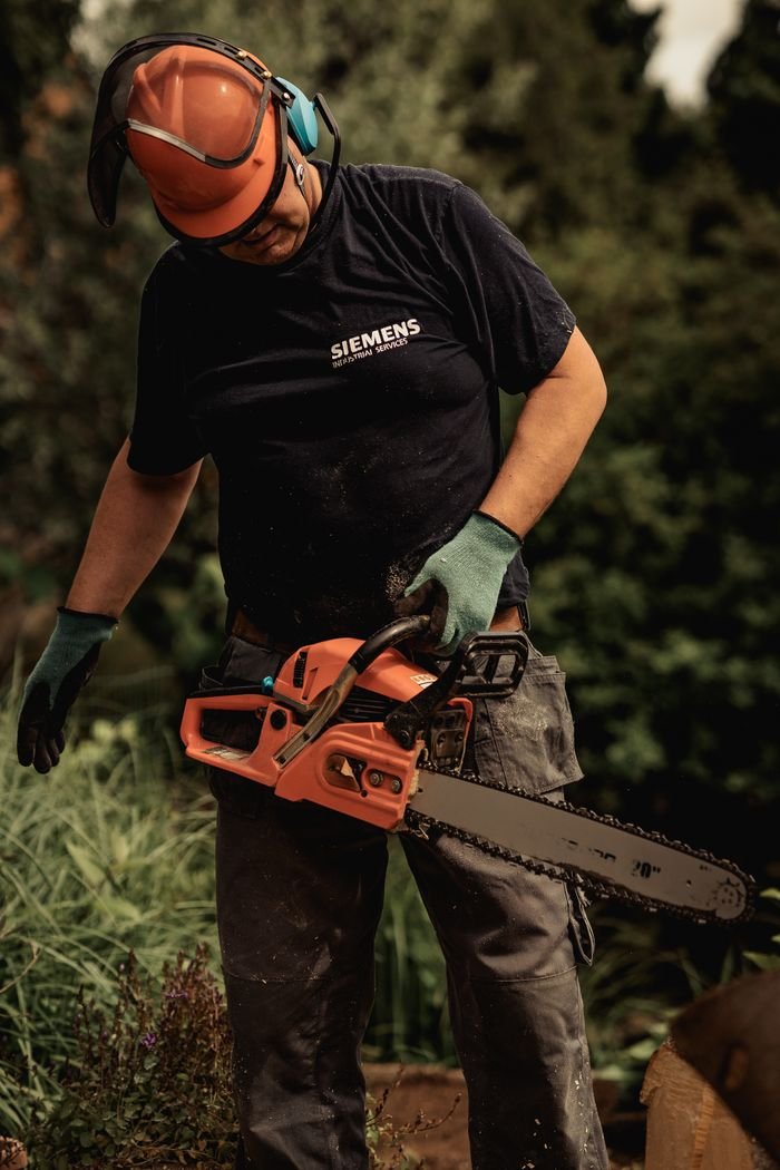 Crafting Captivating Headlines: Your awesome post title goes here Man operating a chainsaw outdoors with safety gear in a forest environment.